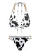 Un ensemble bikini triangle à imprimé vache noir et blanc avec des bretelles décoratives en chaîne dorée sur le haut et le bas échancré.