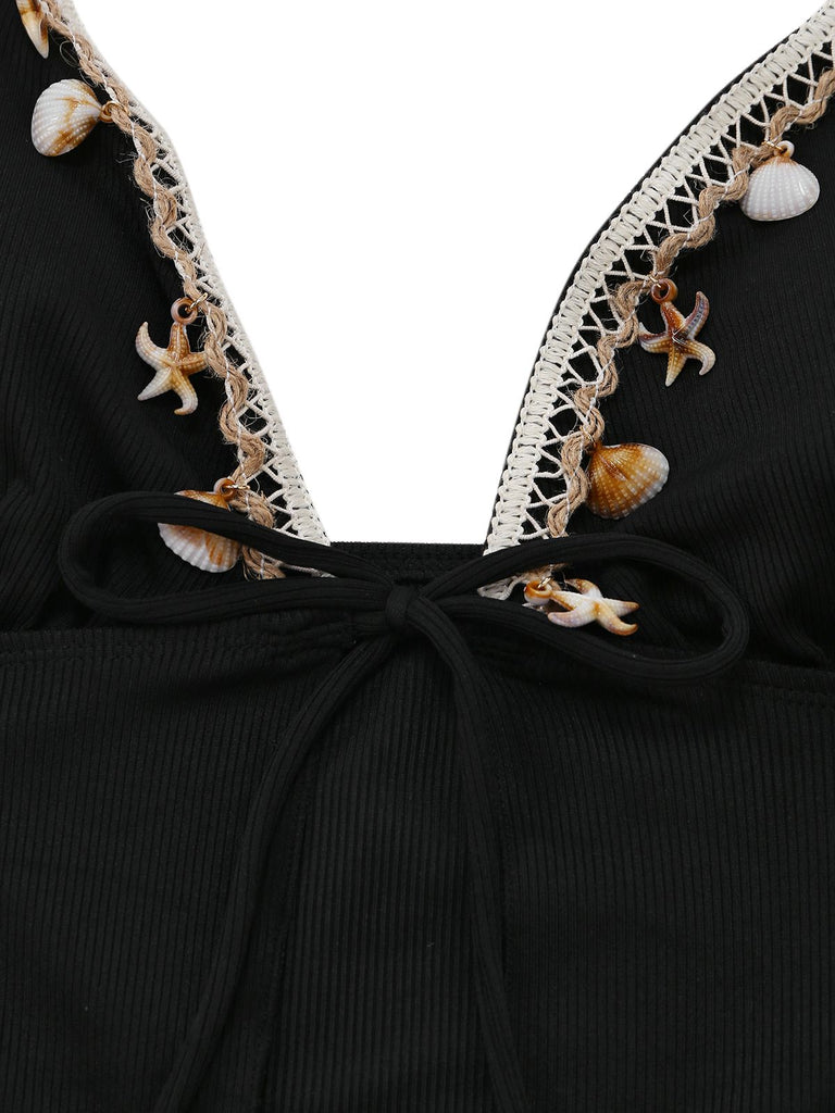 Black dress with white lace trim and shell embellishments on a white background
