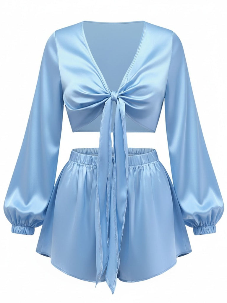 Un ensemble lounge deux pièces en satin soyeux bleu clair, composé d'un haut court à nouer sur le devant avec de longues manches bouffantes et d'un short taille haute assorti.