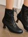 Chaussures noires à lacets portées par une personne sur un parquet.