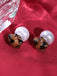Paire de boucles d'oreilles marrons en forme d'étoile à pois blancs sur fond blanc