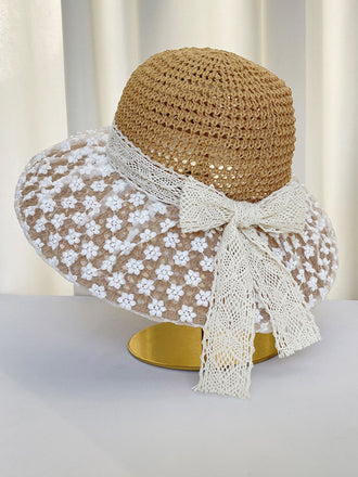 Chapeau de paille orné d'un ruban de dentelle blanche sur fond neutre