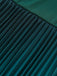 Close-up of pleated teal fabric with a blurred background