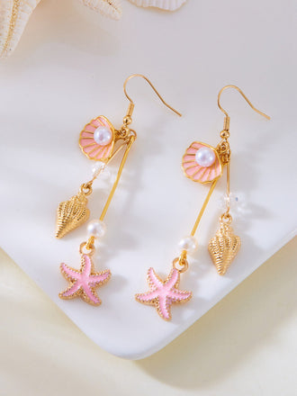 Paire de boucles d'oreilles ornées de coquillages, d'étoiles de mer et de perles sur fond blanc.