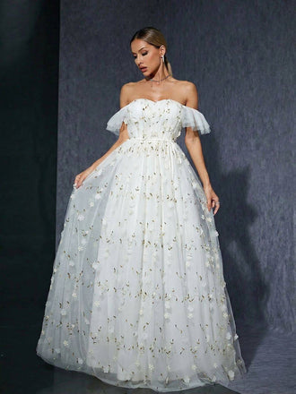 Woman wearing a white off-shoulder gown with floral details against a dark background