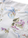 Macro shot of the fabric detail highlighting the intricate blue ribbon and purple floral bouquet pattern.