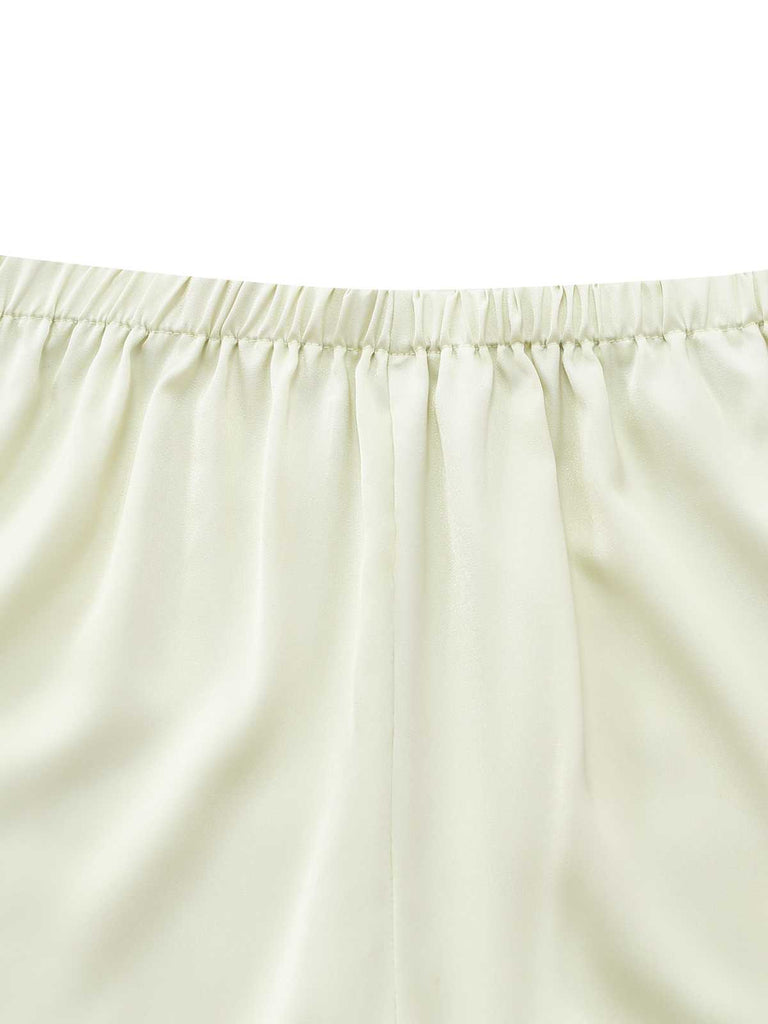Close-up of the gathered elastic waistband on the cream satin pajama shorts.