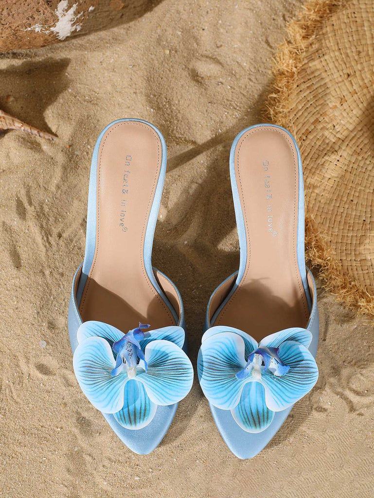 Top-down view of the light blue pointed-toe mules highlighting the intricate petal details of the 3D flower.
