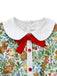 Close-up of the white Peter Pan collar featuring a decorative red velvet-style bow and red buttons.