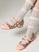 Pink glittery shoes with gold buckles worn with sheer white stockings on a light gray background