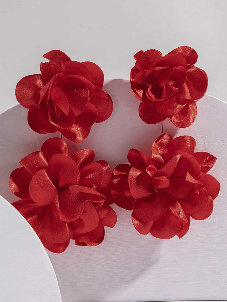 A pair of red statement earrings with multiple tiered fabric flower petals arranged in a cluster on a plain background.