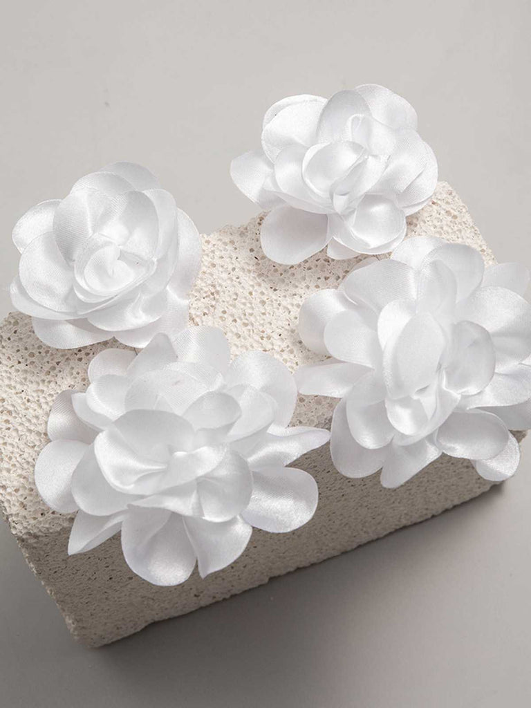 A pair of white oversized statement earrings featuring multiple 3D fabric flowers in a tiered cluster design.