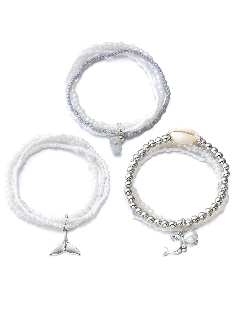 Three white beaded bracelets with silver charms on a white background