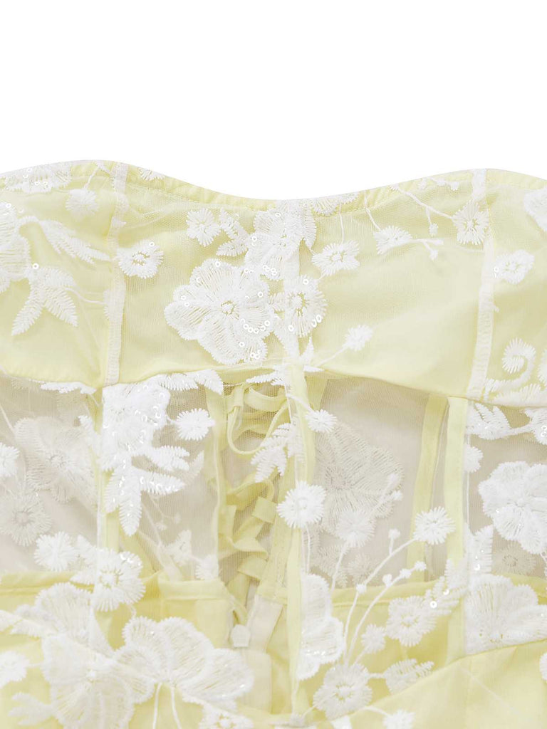 Close-up shot of the bodice area showing the fine white floral lace embroidery on the yellow fabric.